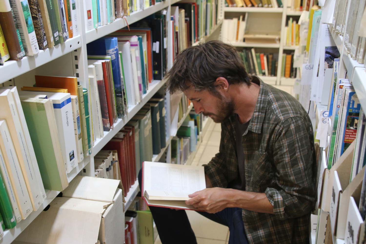 Homme lisant un livre dans la bibliothèque du CBN de Bailleul